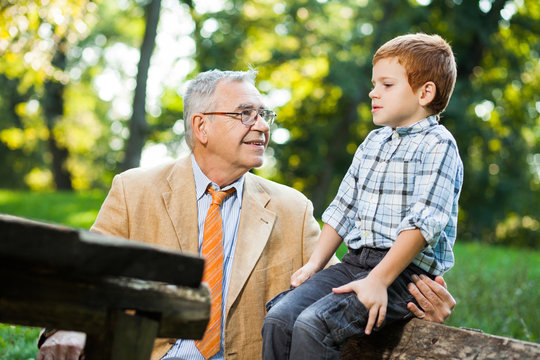 Grandfather and grandson are sitting and talking in park