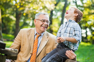 Grandfather and grandson are sitting and talking in park