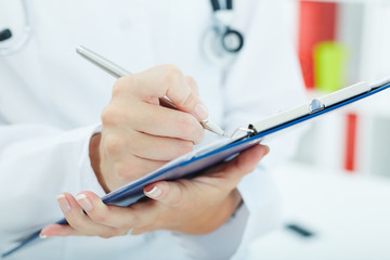Female medicine doctor hand holding silver pen writing something on clipboard closeup. Physician ready to examine patient