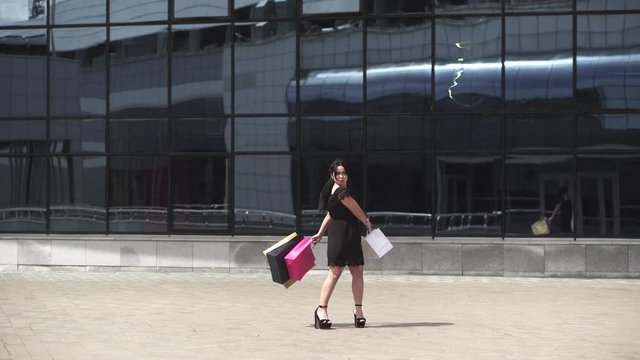 Sale, consumerism: Attractive woman with shopping bags after mall. Timelapse