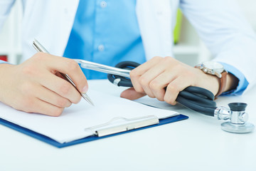 Fototapeta premium Male medicine doctor hand holding silver pen writing something on clipboard closeup. Physician ready to examine patient.
