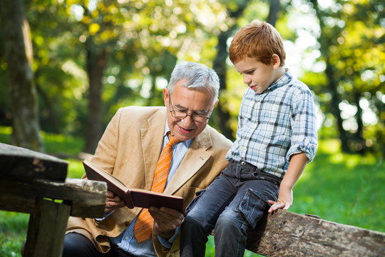 Grandfather and grandson are reading book and learning about nature