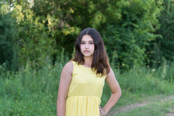 Teen girl in yellow dress standing in the park