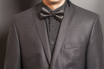 Man in Checkered suit and black and black bow tie on gray backgr