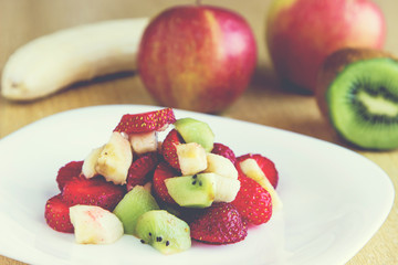 Healthy fruit salad with chocolate and yougurt in white dish. Healthy breakfast, weight loss concept