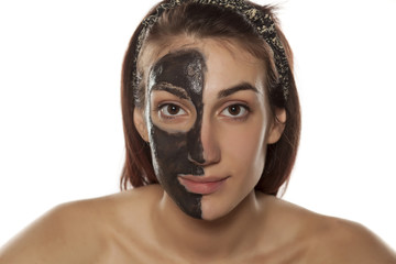 young woman with mud mask on half face