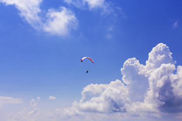 Paraglider flying over clouds