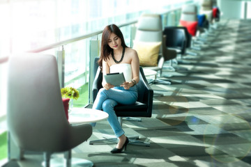 Asia woman,Pretty woman wear blue jeans using tablet at rest area,public place