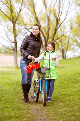 Daughter and mother walk along the shore of the lake with a bike and talk. Family values, education