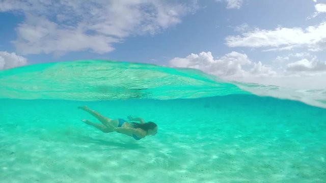 SLOW MOTION UNDERWATER: Young woman swimming in crystal clear ocean