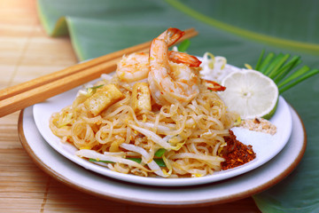 Famous traditional thai food shrimp pad thai, rice noodle stir-fry with prawns, tofu and vegetables on wooden background.