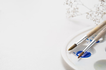 watercolor brushes and pallete on white table