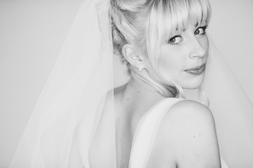 Gorgeous bride with blonde hair looks over her shoulder