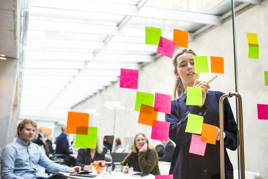 Young businesswoman giving presentation to colleagues in office
