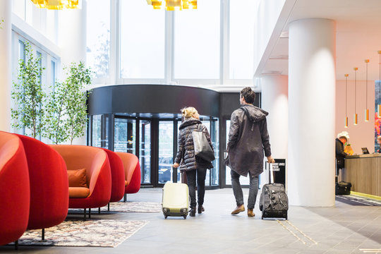 Rear view of business people with luggage walking at hotel lobby