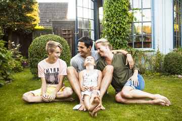 Happy family sitting on lawn in front of house