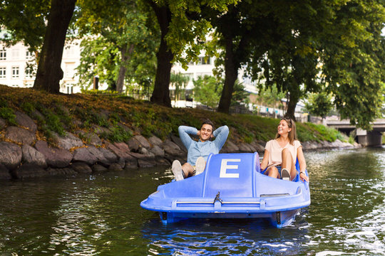 Friends enjoying pedal boating on river in city