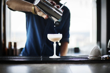 Bartender pouring cocktail from shaker into glass