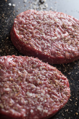 Meat for burgers, grilling, barbecue, bbq. Fresh, spicy, uncooked, delicious beef for hamburgers on dark background with copy space closeup