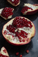 Red juicy pomegranate on dark marble background. Healthy, antioxidant, fresh, gourmet, delicious, organic fruit. Ingredient for grenadine. Close-up and copy space.
