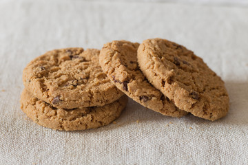 Cookies pile with chocolate chip on light textile background. Delicious morning snacks for breakfast, brunch and lunch. Appetizing, healthy, sweet, scrummy, and fast food.
