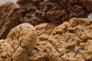 Cookies pile with chocolate chip on light textile background. Delicious morning snacks for breakfast, brunch and lunch. Appetizing, healthy, sweet, scrummy, and fast food.