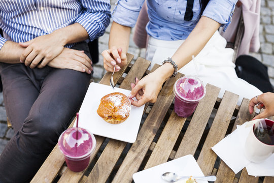High angle view of couple having cupcake and smoothies at sidewalk cafe