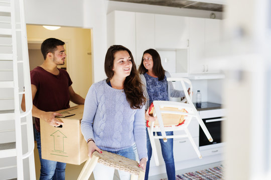 Woman With Friends Moving Furniture In New Home