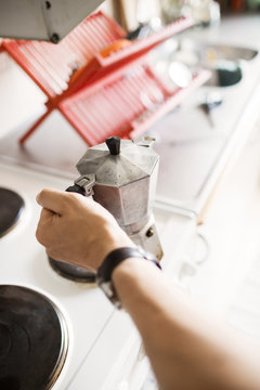 Cropped image of man's hand holding coffee maker at kitchen counter