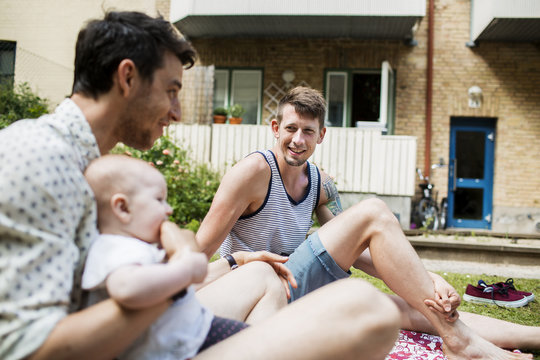 Two men with baby girl having picnic outdoors