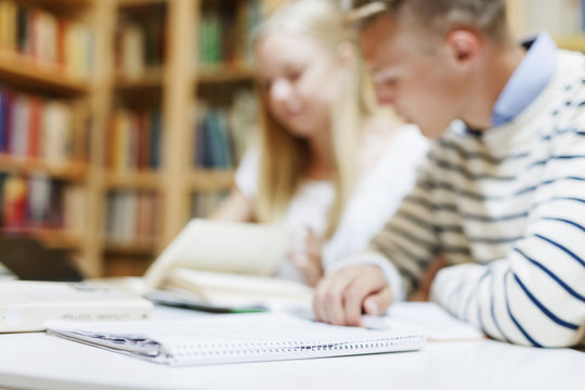Male and female students learning at desk in classroom