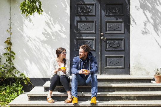 Couple sitting on steps in front of old door