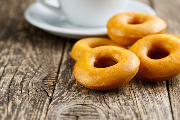 Orange vegetarian donuts with coffee for breakfast on wooden tab