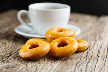 Orange vegetarian donuts with coffee for breakfast on wooden tab