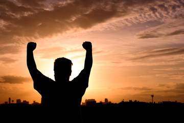 silhouette of man show arm up for achievements successful and celebrating success with sunrise