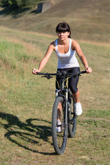 Fototapeta premium Young lady with bicycle on a spring meadow