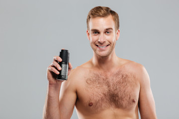 Fototapeta premium Smiling handsome man holding deodorant