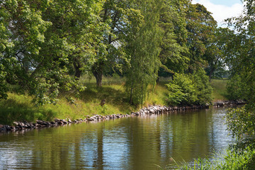 Lush riverside with reflections. Sweden