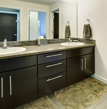 Bathroom interior with black cabinets, two sinks and large mirror.