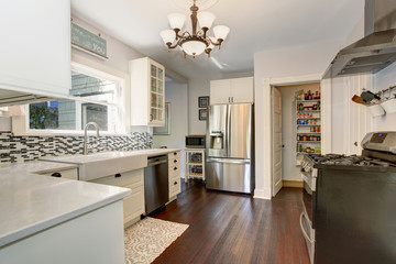 White kitchen room with stainless steel fridge and hardwood floor.