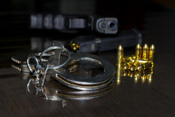 Police handcuffs with a gun and ammo on the table