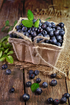 blueberries in basket on a wooden surface.