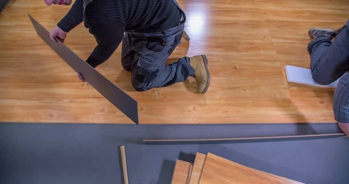 A young man is making wood flooring for the studio that he's about to build inside a house. Close-up shot.
