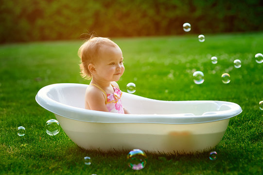 little girl bathes in a bath with soap bubbles