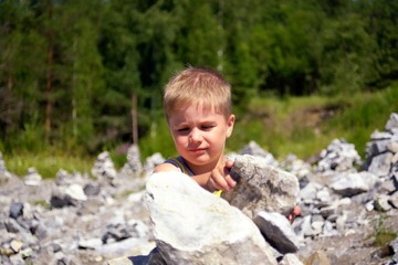 Little cute boy building tower of stones