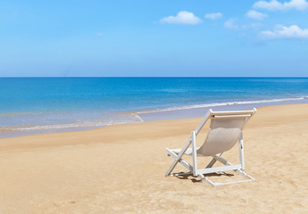 Fototapeta na wymiar Empty white wooden beach chair on tropical beach with blue sky 