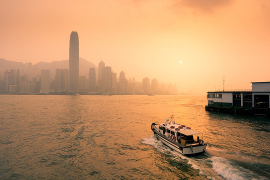 Hong Kong business district with sunset and sailing boat.