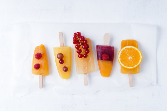 Fruits and different homemade ice lollies made of fruit juice and pulp