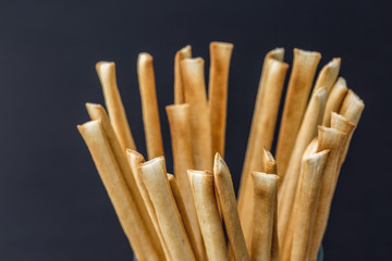 Grissini (Italian breadsticks) in a glass on black background