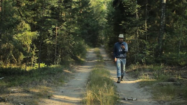 A man walks through the forest with the phone and looks at the navigation application. He chooses the right direction